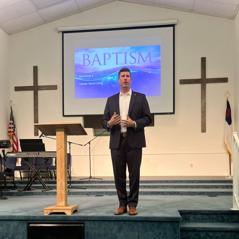 Pastor Kevin talking about baptism on stage at Trinity Baptist Church