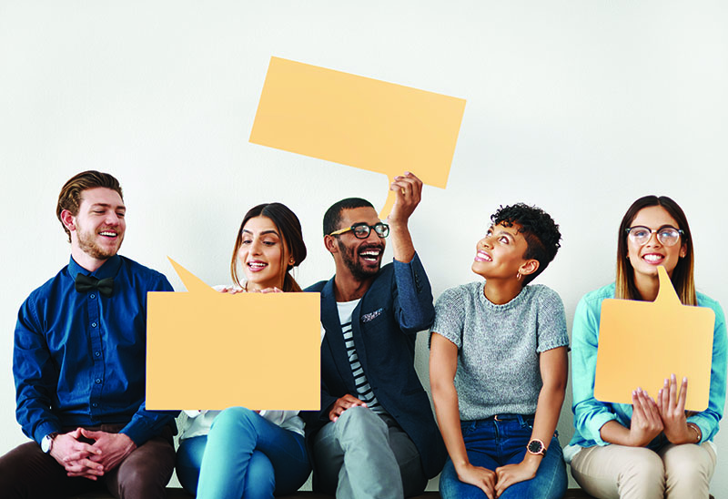 Young adults holding up paper speech bubbles.